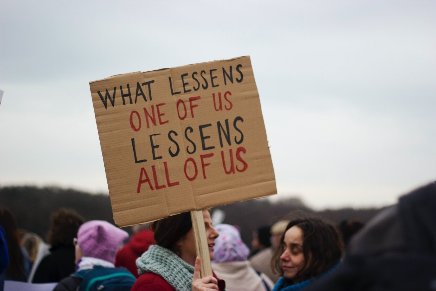 At a protest, a woman holds a sign saying 